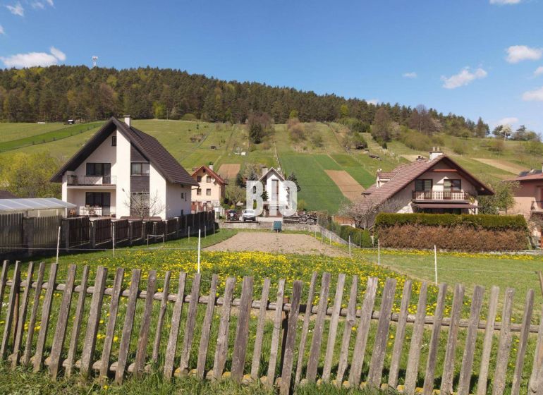 Lands - housing in Bytča with country houses, a fence, and green pastures in the background.