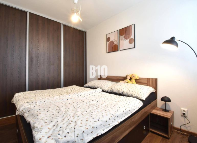 A bedroom in a 3-room apartment with a built-in wardrobe and a bed with a wooden decor.