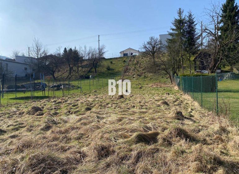 A plot for residential use in Radoľa surrounded by grass and fencing, ideal for construction.