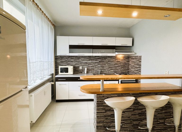 Kitchen in a studio apartment, bright interior, kitchen unit, chairs at the bar.