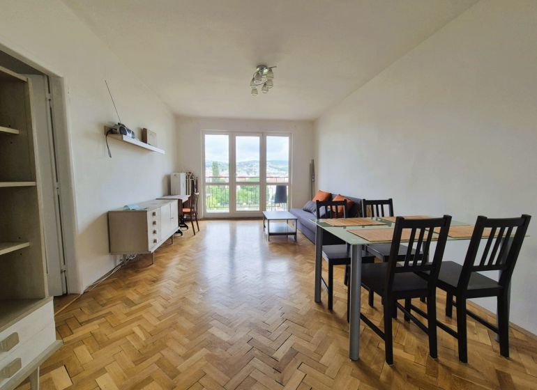 Living room in a 3-room apartment with a wood-patterned floor and a dining table.
