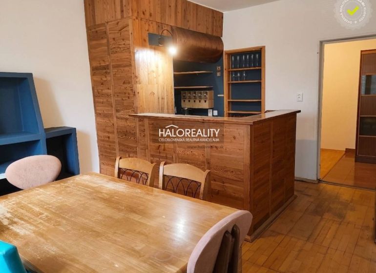 Dining room in a 3-room apartment with a wood-patterned floor and a wooden bar.