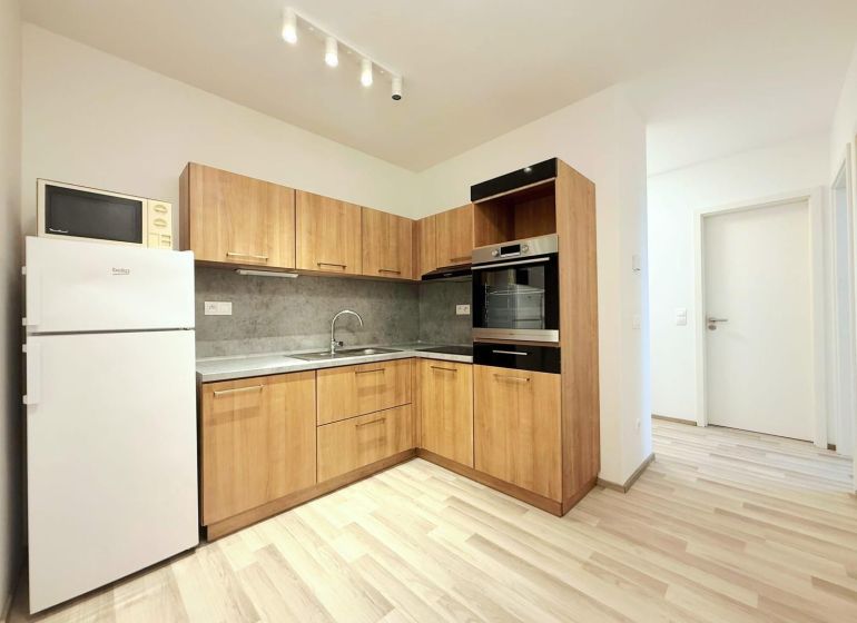 A kitchen in a 2-room apartment with wooden decor and appliances including a microwave.