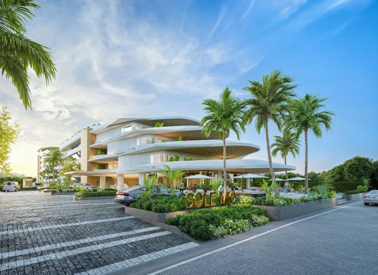 Apartment construction in Phuket with modern architecture, surrounded by palm trees and parking space.