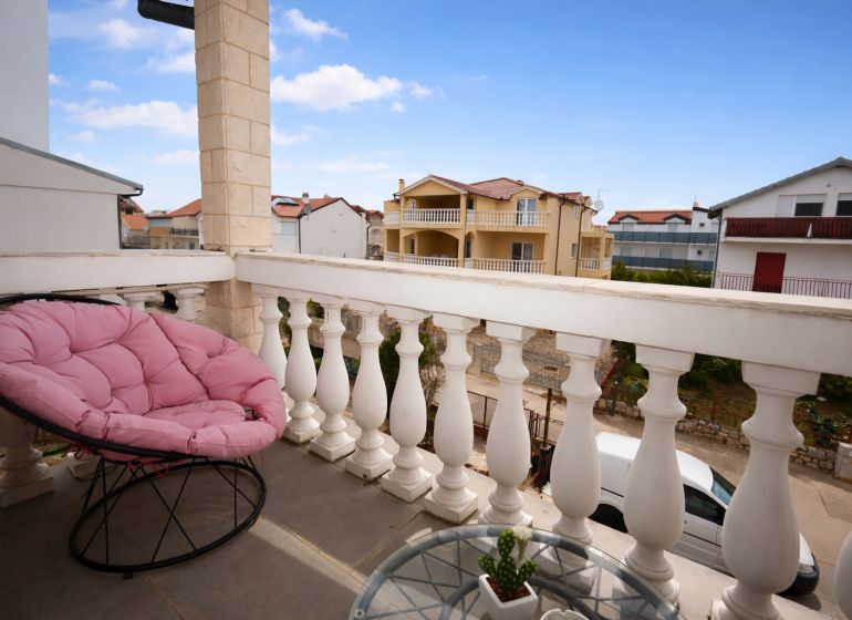 Balcony of a holiday apartment in Vodice, comfortable chair with a view of the buildings.