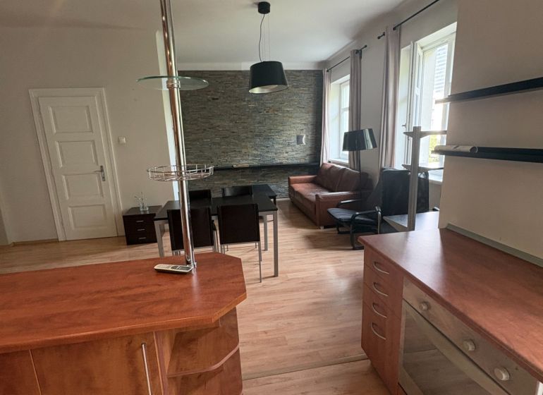 The kitchen of a 2-room apartment with a wooden decor floor and a modern counter.