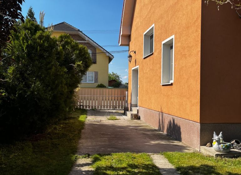 A family house in Čalovec with an orange facade, a lawn, and a paved driveway.