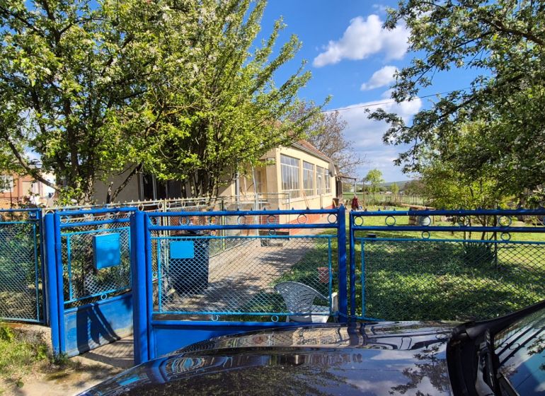 A family house in Dedinka with a blue gate and a garden full of greenery.