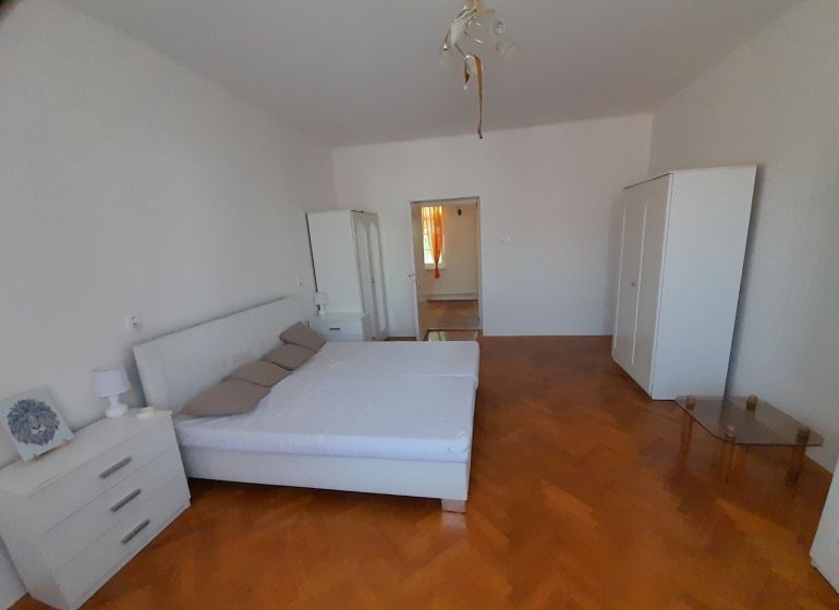 A bedroom in a 4-room apartment with light furniture and a wooden decor floor.