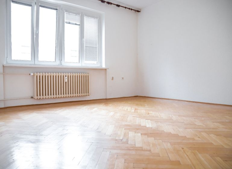 A room in a 2-room apartment with a large window and a floor with a wooden decor.