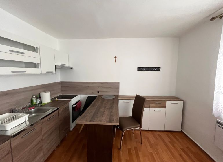 Studio apartment with a kitchenette and a wooden decor floor and a dining table.
