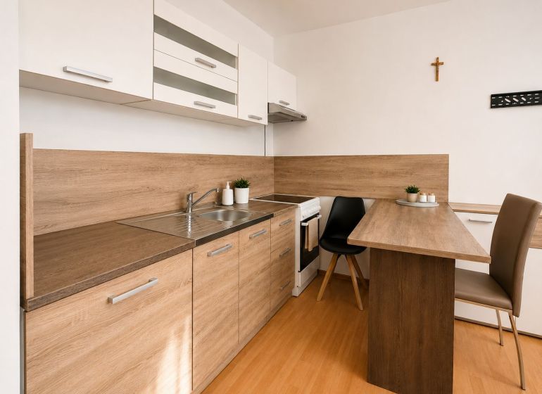 Kitchen unit in a studio apartment with a wooden decor floor and a dining table.