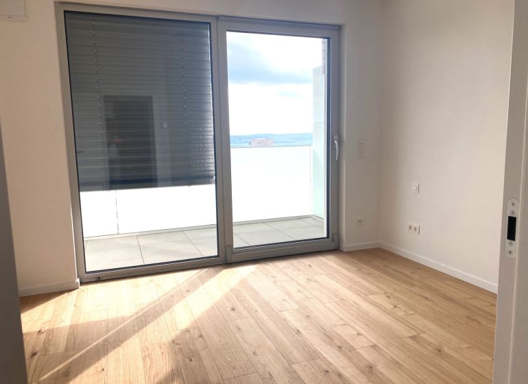 Interior of an office with wood-patterned flooring and a large window.