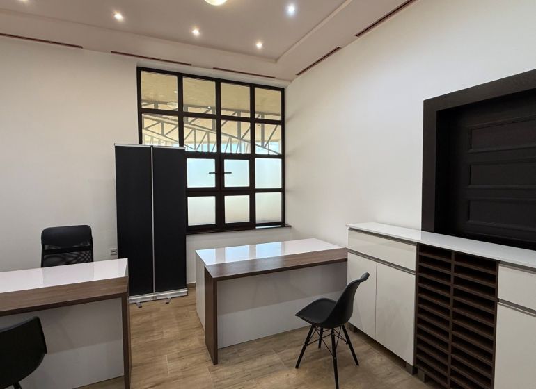 Offices with wood-patterned flooring, simple interior, white walls, black chairs.