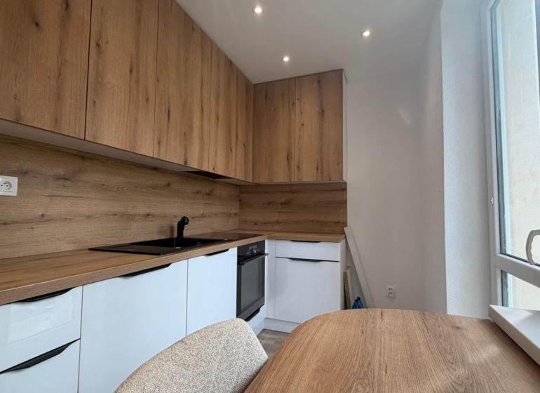 A kitchen in a 3-room apartment with a wooden decor floor and a built-in unit.