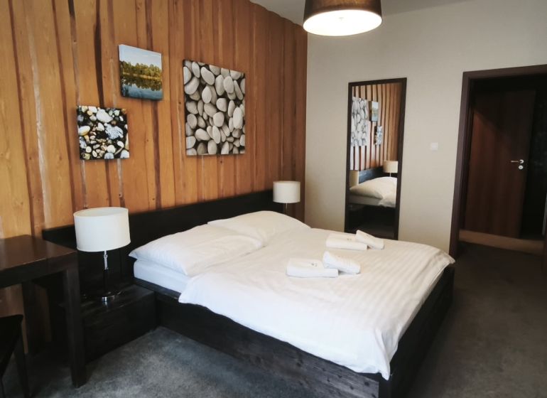 Bedroom with a double bed and wooden paneling in a Holiday Apartment.
