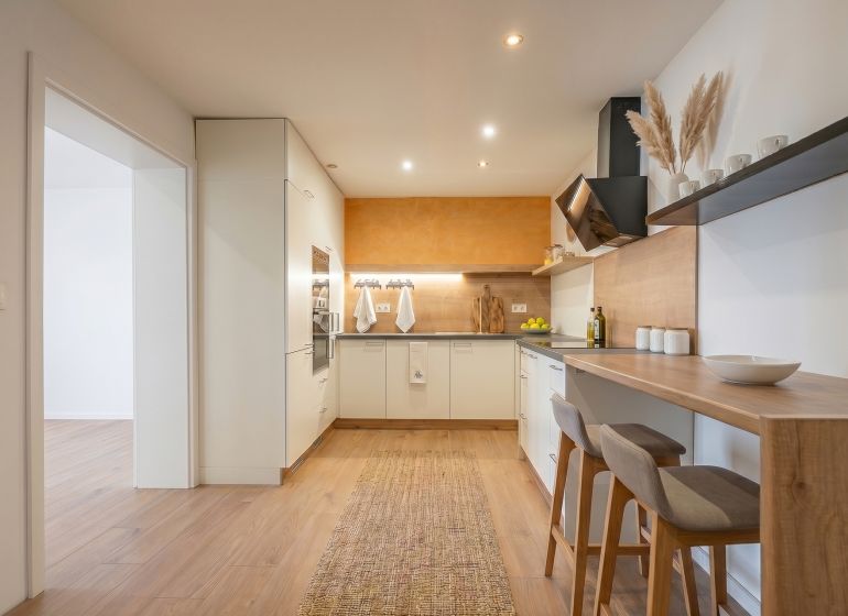 A kitchen in a family house with a bar counter and a wooden decor floor.