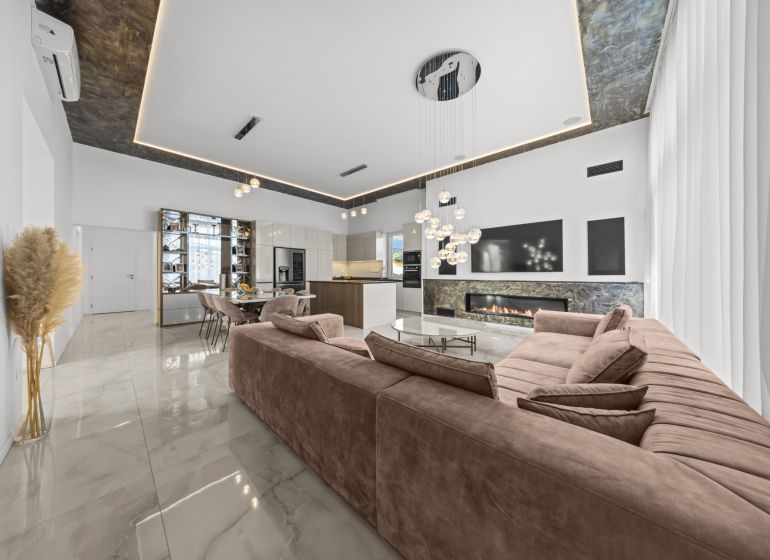 Spacious living room with a fireplace in a family house, with a marble floor.