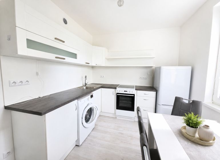 A kitchen in a 2-room apartment with white cabinets and a wood-patterned floor.