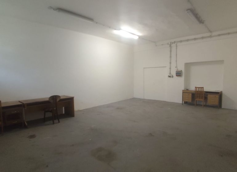 Empty room with tables and chairs in warehouse and hall spaces.