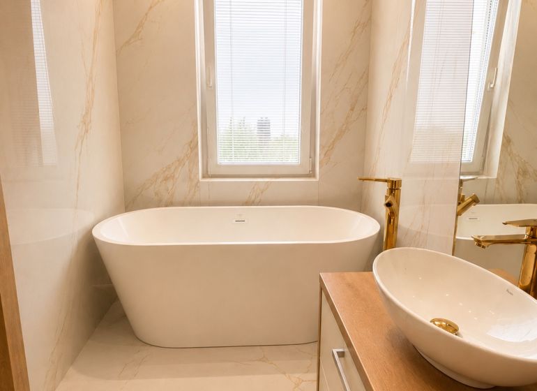 Bathroom with a bathtub and a sink in a 3-room apartment, light marble decor.