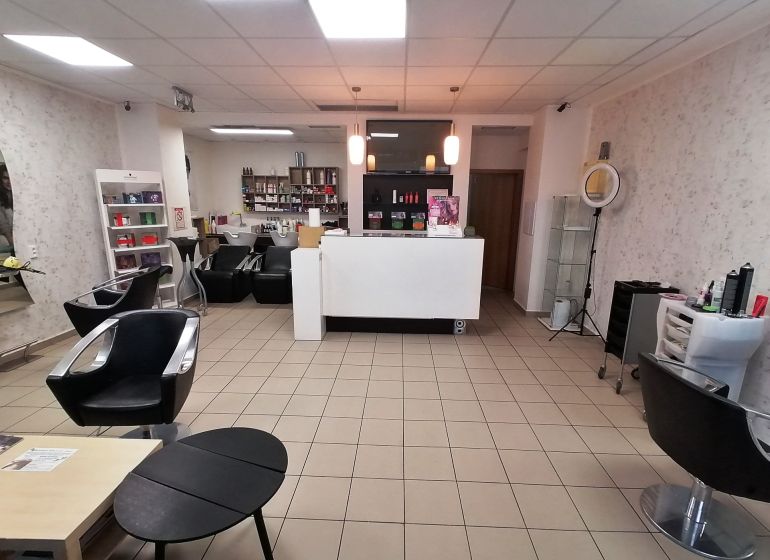 Interior of commercial premises with hairdressing equipment, sofas, and shelves with products.