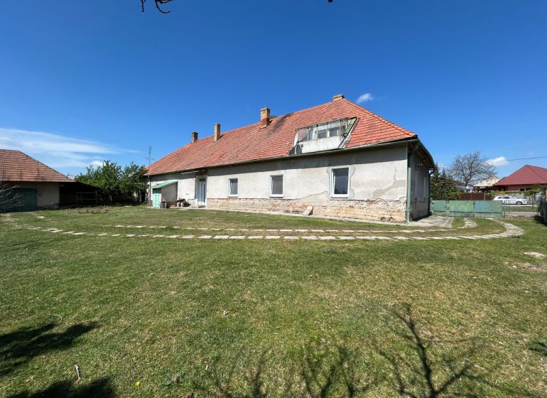 A family house in Čifáre with a large garden and a brick roof under a blue sky.
