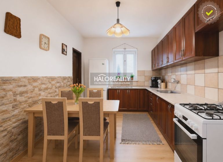 A kitchen in a family house with a wooden decor floor, a dining table, and a kitchen unit.