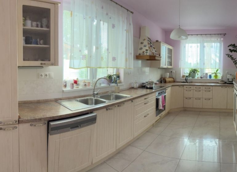 A spacious kitchen in a family house with wooden cabinets and many windows.