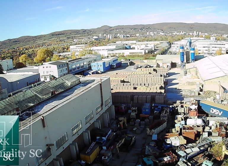 A view of warehouses and halls on Staviteľská Street in Bratislava III surrounded by trucks and materials.