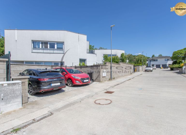 A street with family houses in Stupava, parked cars, clear weather.