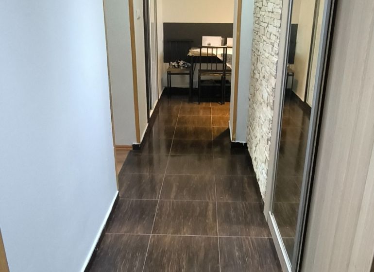 A hallway in a 3-room apartment with glossy tiles and a mirrored wardrobe.
