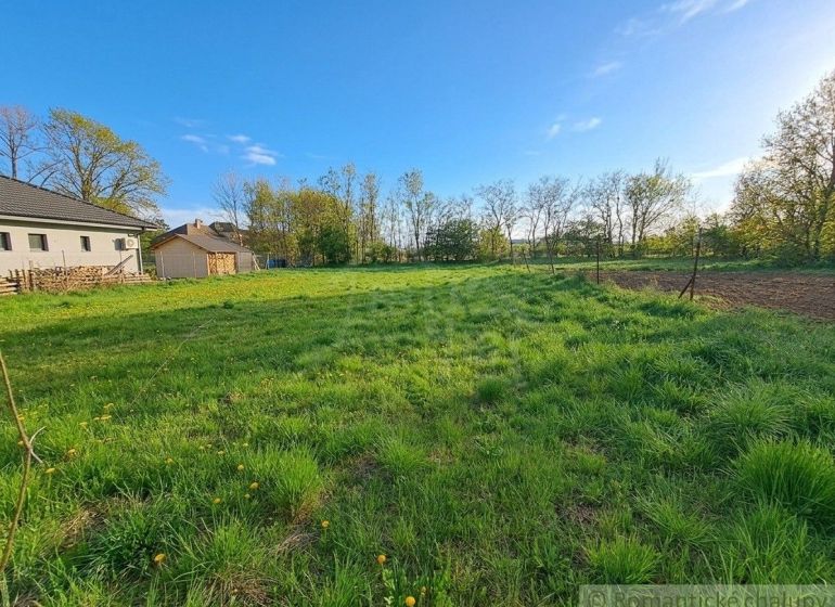 Vast green gardens in Hruboňovo surrounded by trees and houses on a sunny day.