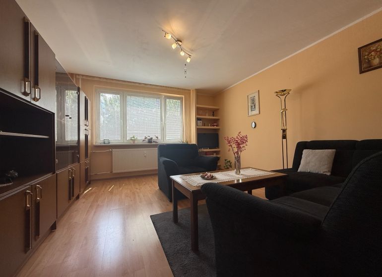 Living room in a 3-room apartment with a wooden decor floor and a comfortable sofa set.