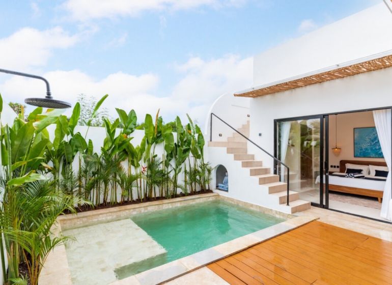 Villa in Bali with a pool surrounded by greenery, wooden terrace decor, outdoor shower.
