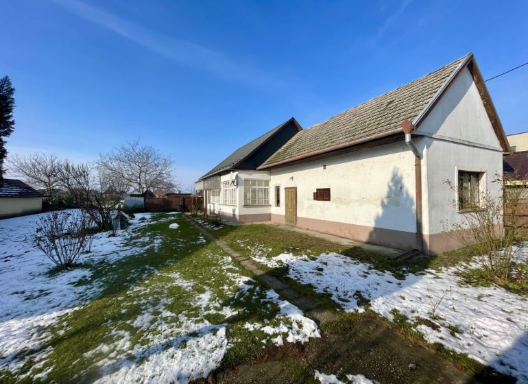 A family house in Vrakúňa surrounded by a garden with a lawn and remnants of snow.