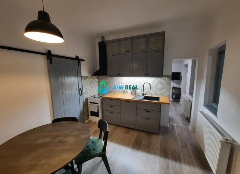 A kitchen with a wooden decor floor in a family house, with gray cabinets and a table.