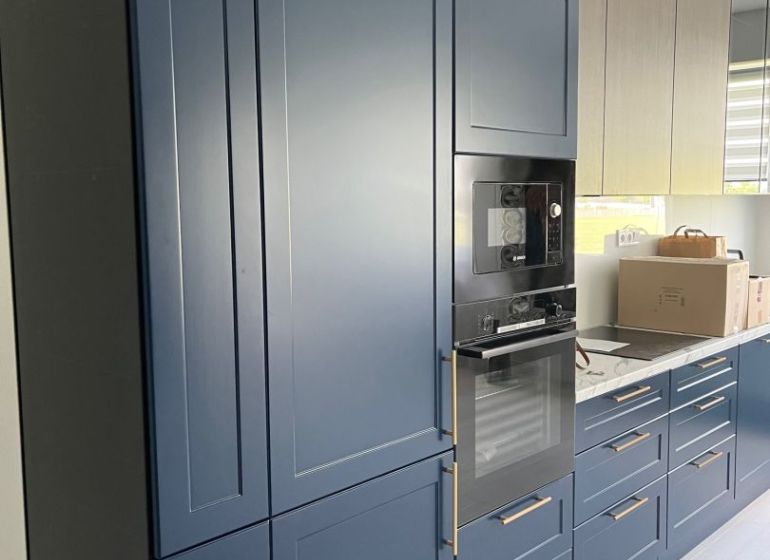 A kitchen in a 3-room apartment with dark blue built-in cabinets and appliances.