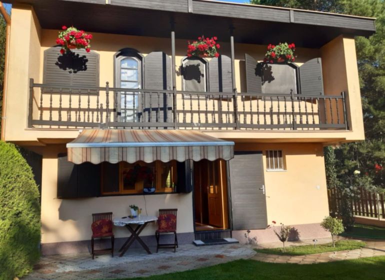 A family house in Gabčíkovo with a balcony, an awning, and flowers on the windows.