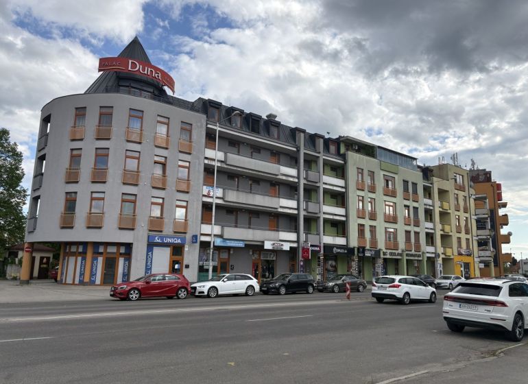 A building with shops on Galantská cesta in Dunajská Streda, cars parked in front of it.