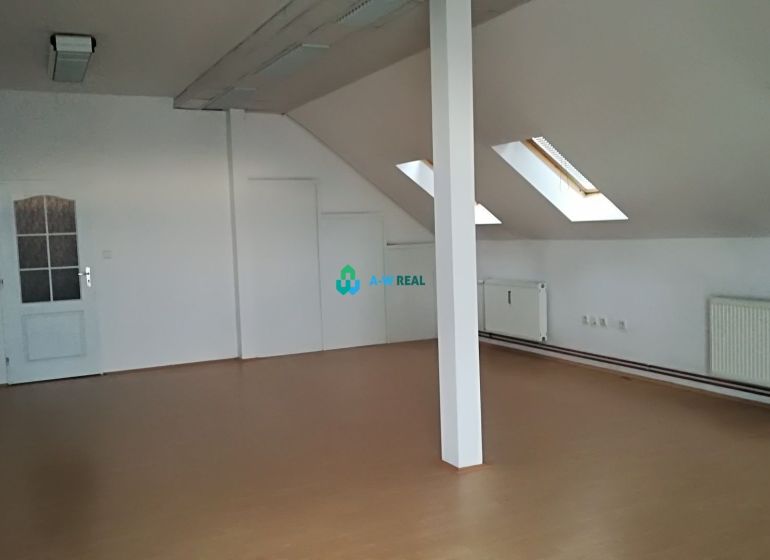 Attic office with white walls and a wooden decor floor.