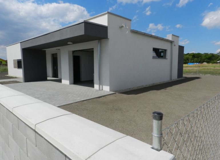 A family house in Dolný Bar with a fence and a paved area under the blue sky.