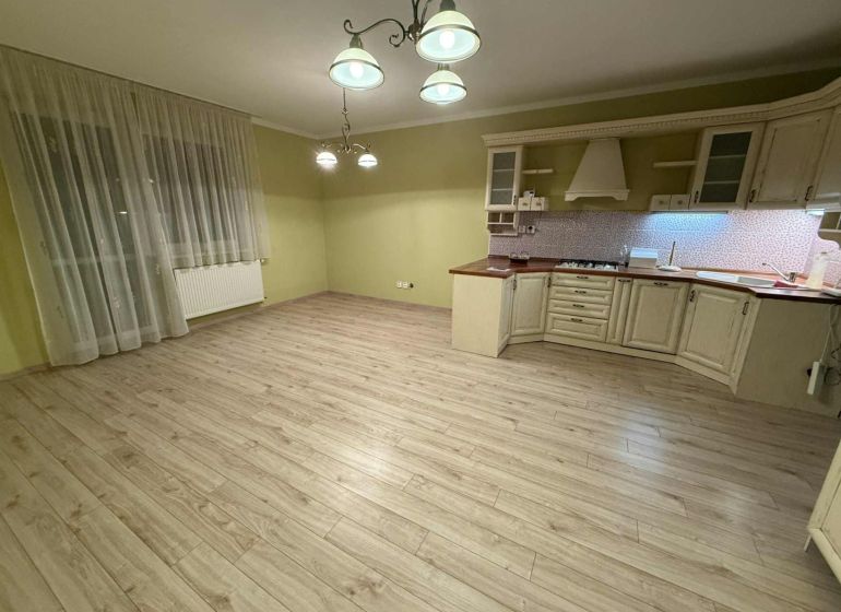 A kitchen in a 3-room apartment with a wooden decor floor and light fixtures.
