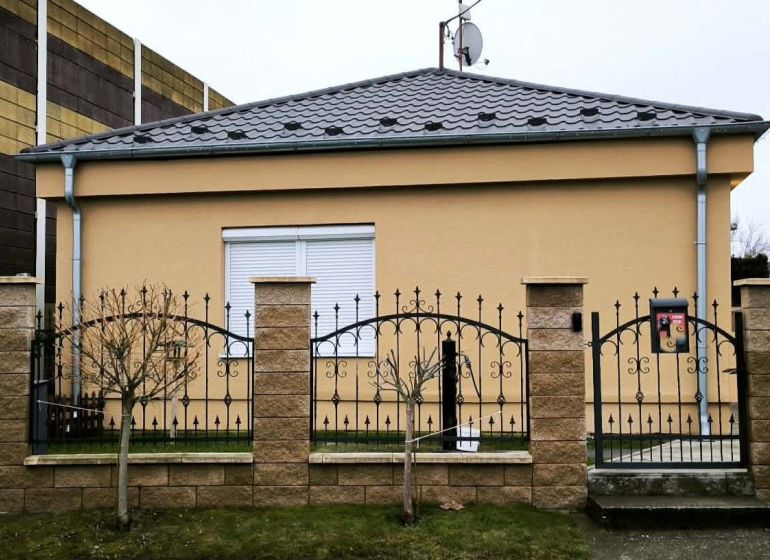 A family house in Ohrady with a stone fence and a satellite dish on the roof.