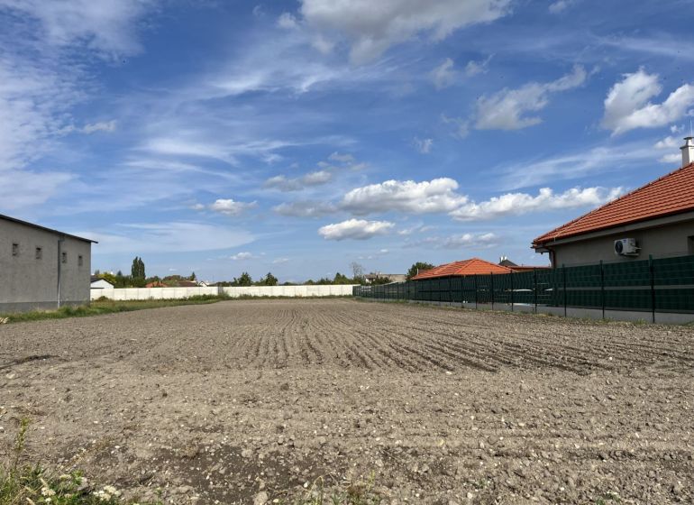 Plots - housing in Holice, between houses with red roofs and blue sky.
