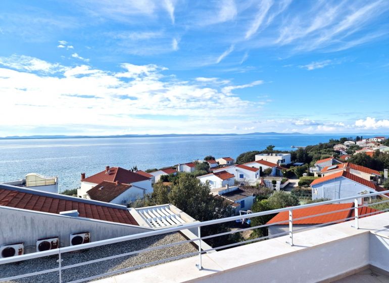 A view from a 3-room apartment in Petrcane of the sea and rooftops of houses.