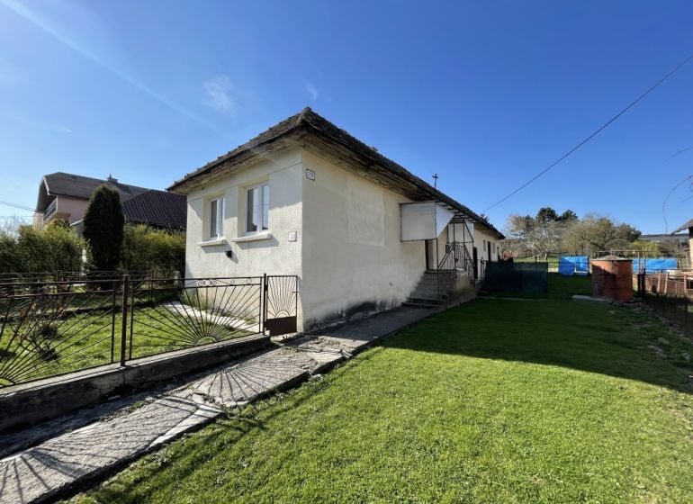 A family house on Tehelná Street in Drienov, surrounded by a well-maintained garden and a fence.