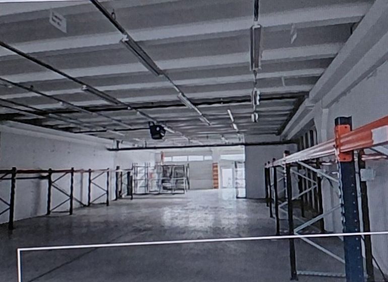 Spacious warehouses and halls with metal shelves and concrete floors.