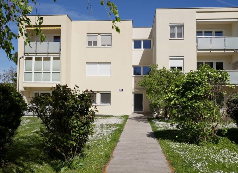 Apartment building on Spechtgasse in Mödling with a garden and a walkway in the foreground.