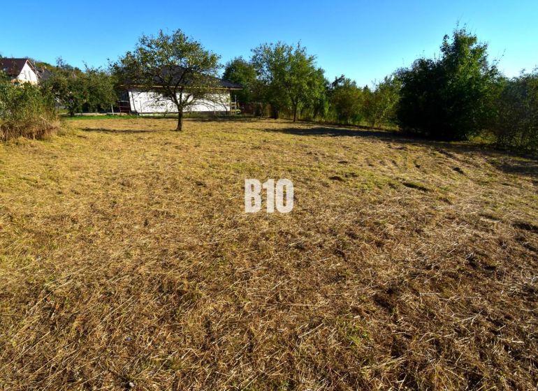 A plot for residential use in Moravské Lieskové with well-maintained green grass and trees.